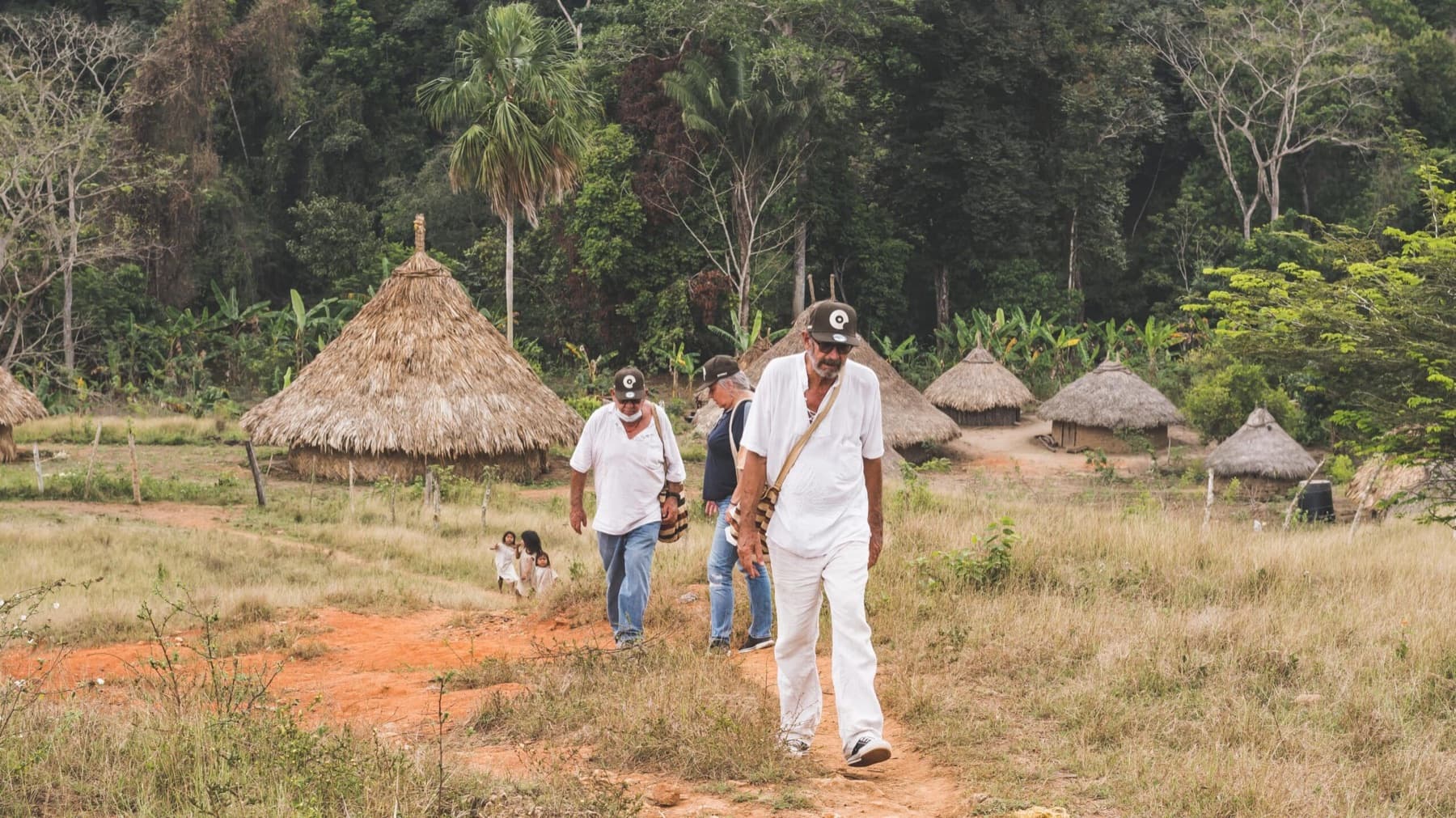 Foundation visitors walk along a dirt path in the Kogui community