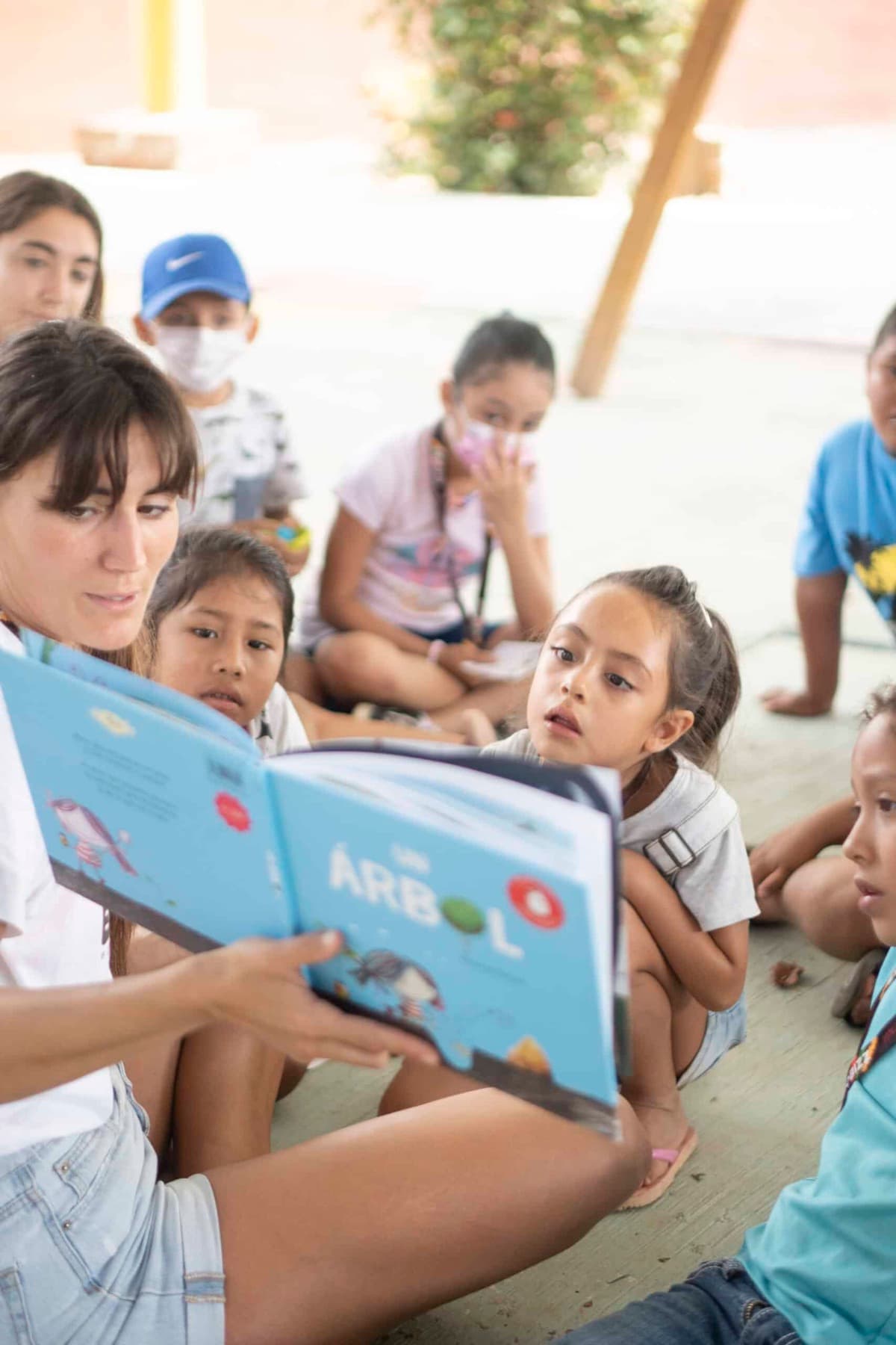 An educator reads a book about trees to a group of children